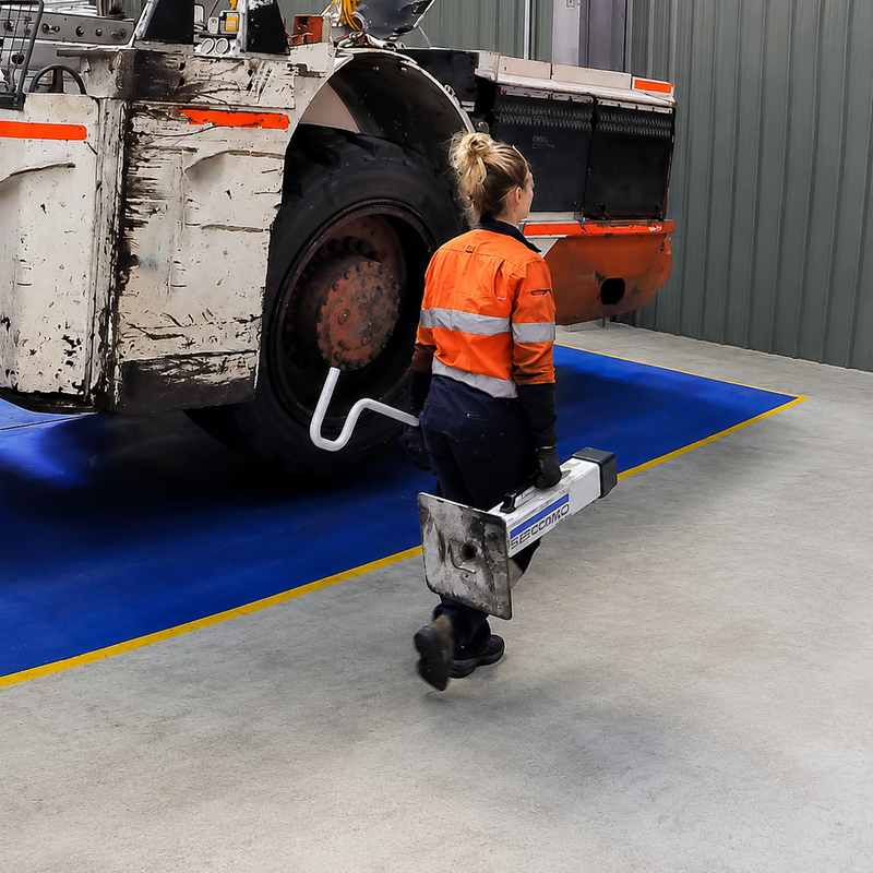 Technician carrying a 25t Composite Support Stand with a placement hook beside a Sandvik Eimco LHD
